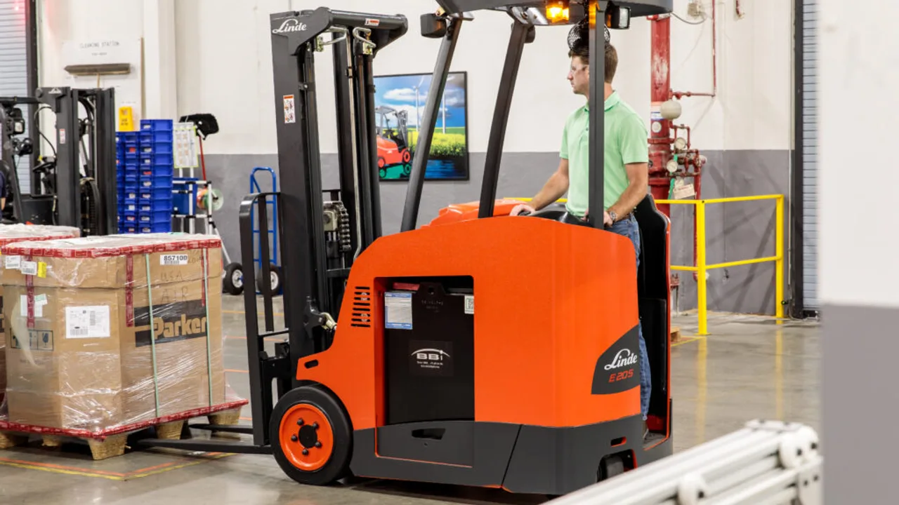 An operator on a red Linde electric order picker collecting stock in a warehouse, with Linde branding on the overhead guard